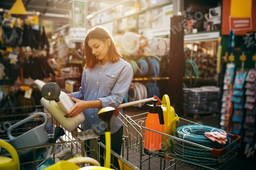 Preview: Female buyer choosing tools in shop for gardeners