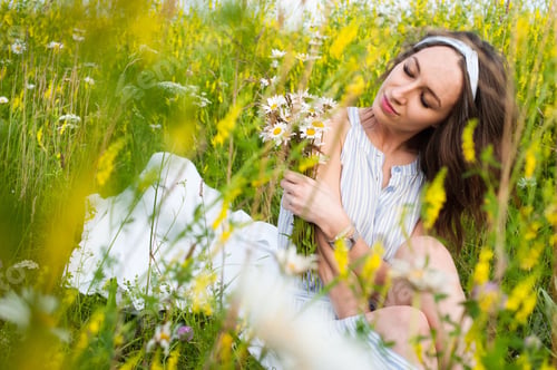 Preview: beautiful girl with flowers sitting in green field