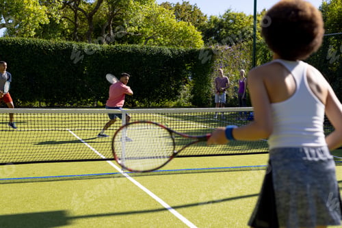 Preview: Happy diverse group of friends playing tennis at tennis court