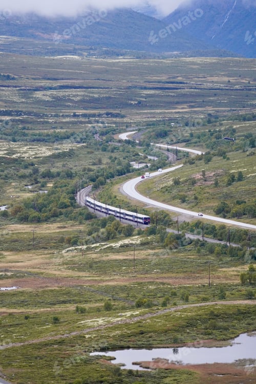 Preview: Scenic train journey through lush green valley with mountains.