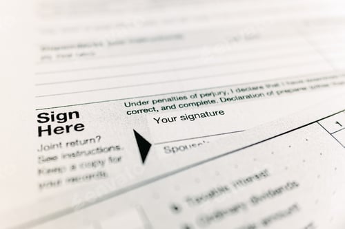 Preview: Sign here text on a government tax form.