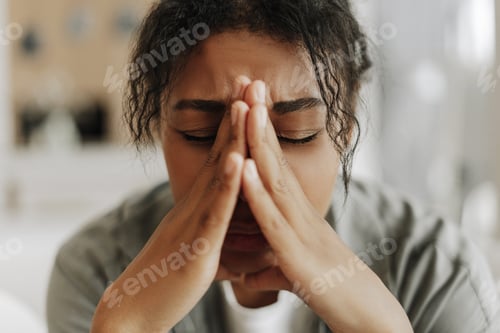 Preview: Young black woman suffering stress holding hands on face