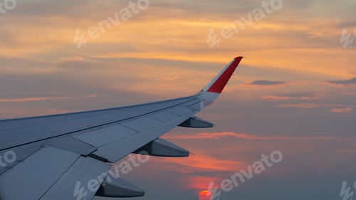 Preview: Aerial view of along passenger plane wing flying above beautiful sunset.
