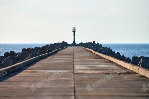 Preview: Empty long concrete pier with breakwaters and signal lighthouse in European port, copy space