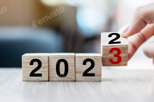 Preview: hand flipping block 2022 to 2023 text on table.