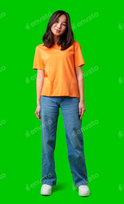Preview: Young woman wearing orange shirt and blue jeans standing against bright green background