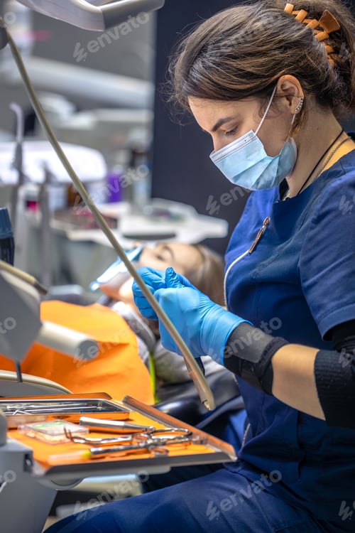 Preview: Young female dentist in dental office. Dentist at work. Dental treatment concept.