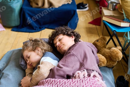 Preview: Adorable boy with blond curlt hair and his mother sleeping on the floor