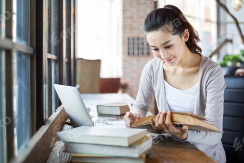 Preview: Young woman studying in cafe