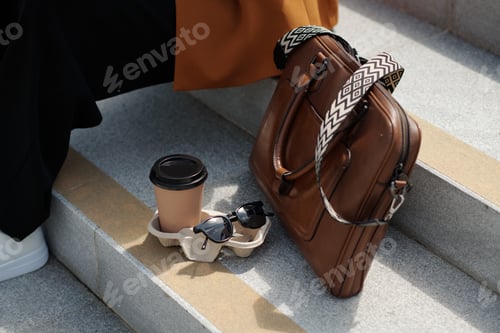 Preview: Composition of sunglasses, cup of coffee and brown leather handbag