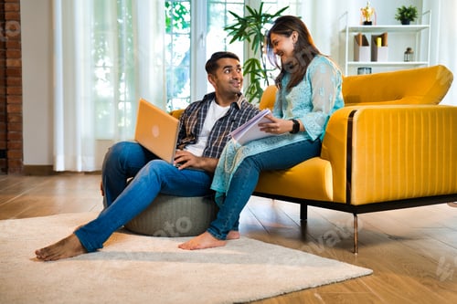 Preview: Indian Asian couple happily budgeting and working on finances with laptop and documents at home