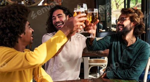 Preview: Small group of multiracial friends toasting with beers together in a bar.