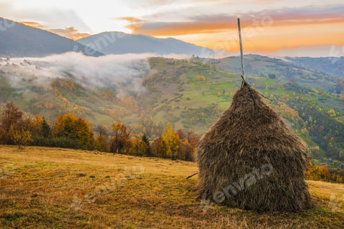 Preview: Majestic sunrise in misty morning valley with haystack on grassland hill