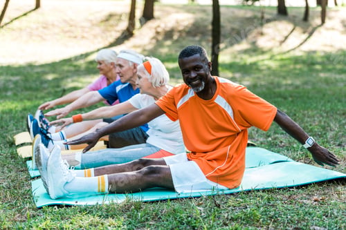 Preview: selective focus of multicultural retired men and woman in sportswear exercising on fitness mats