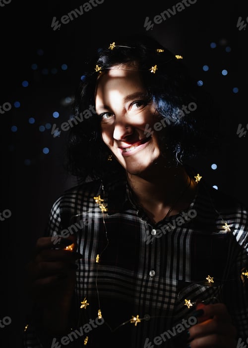 Preview: Portrait of a beautiful young woman with fairy lights with a shadow pattern on the face and body
