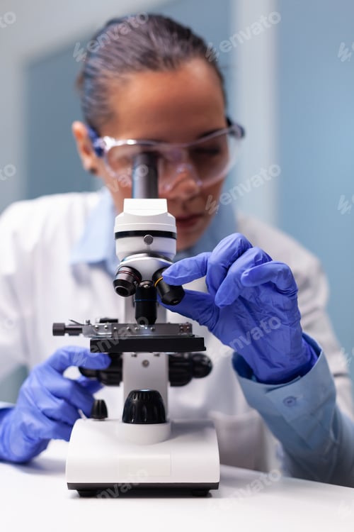 Preview: Scientist woman doctor analyzing coronavirus test results using medical microscope