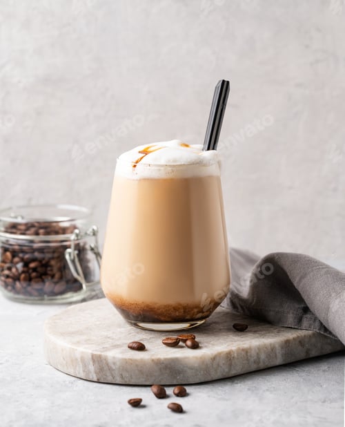 Preview: Cappuccino or latte with milk foam and caramel in a glass with coffee beans on marble background