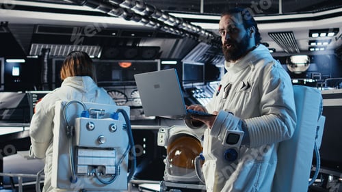 Preview: Astronaut reviewing onboard analytics on laptop before stepping out of station