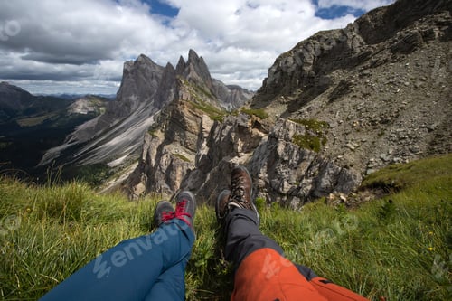 Preview: Trekking boots of a hiker couple while sitting on top of a mountain in Seceda, Dolomites, Italy