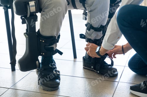 Preview: Mechanical exoskeleton, physiotherapist placing the tapes on the legs the disabled robotic skeleton