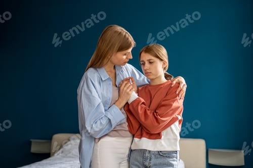 Preview: Worried loving woman mother hugging upset teenage girl daughter, listening and supporting child