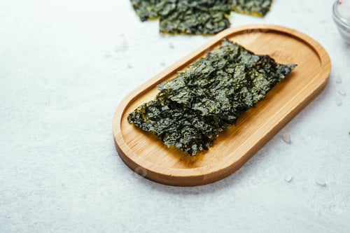 Preview: Nori seaweed snack on wooden tray with salt and scattered flakes