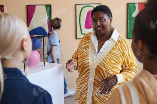 Preview: Scool children listening to teacher or tour guide in modern art gallery