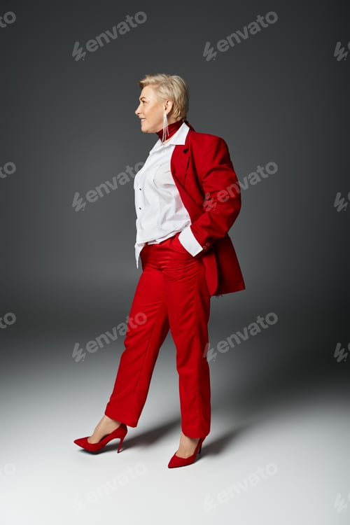 Preview: Stylish adult woman in elegant red suit showcasing confidence in a contemporary studio setting
