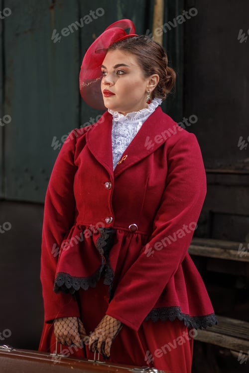 Preview: A girl in a burgundy suit and a hat stands with a suitcase near an old steam locomotive.Vintage