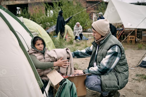 Preview: Young female volunteer passing clothes to child
