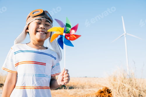 Preview: Boy's playful fascination near wind turbines holding a pinwheel toy highlights joy of wind energy