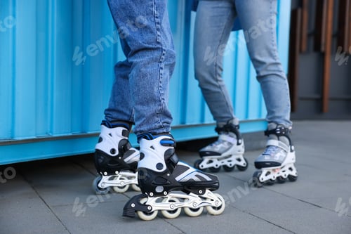 Preview: Couple with roller skates near light blue wall outdoors, closeup