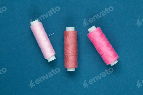 Preview: Pink sewing needles on blue background
