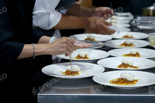 Preview: chefs in a professional kitchen garnishing dessert plates with precision.