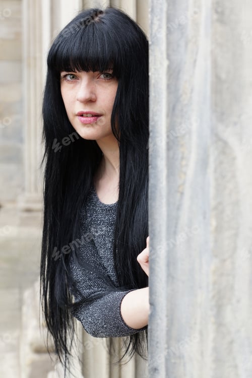 Preview: woman peeking out from behind a pillar