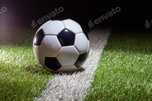 Preview: Soccer ball low angle view on white stripe of grass field with dramatic lighting and dark background