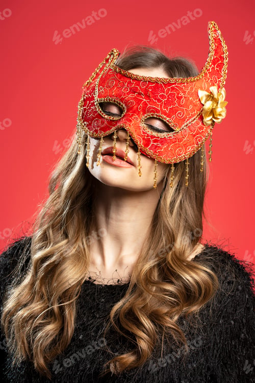 Preview: Young woman wearing red and gold venetian mask with closed eyes on red background