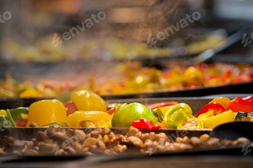 Preview: Hot and delicious healthy food with capsicum bell peppers cooking at winter market with steam rising