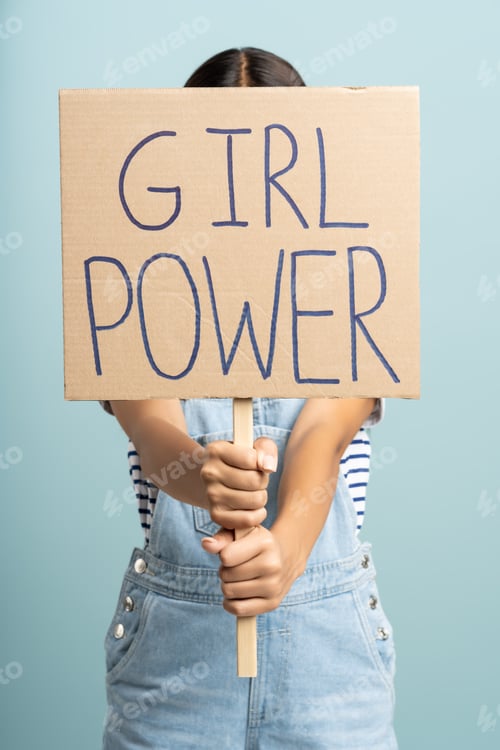 Preview: Anonymous woman holding banner GIRL POWER slogan isolated on studio blue background. Women's rights