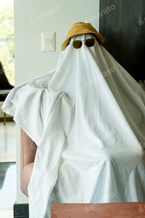 Preview: Person wearing a hat and black-rimmed sunglasses over a white cloth resembling a ghost
