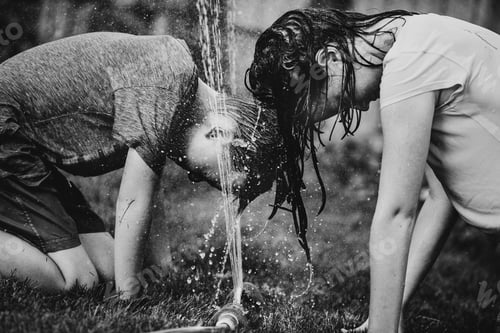 Preview: Young boy and young girl playing in the backyard with the garden sprinkler.