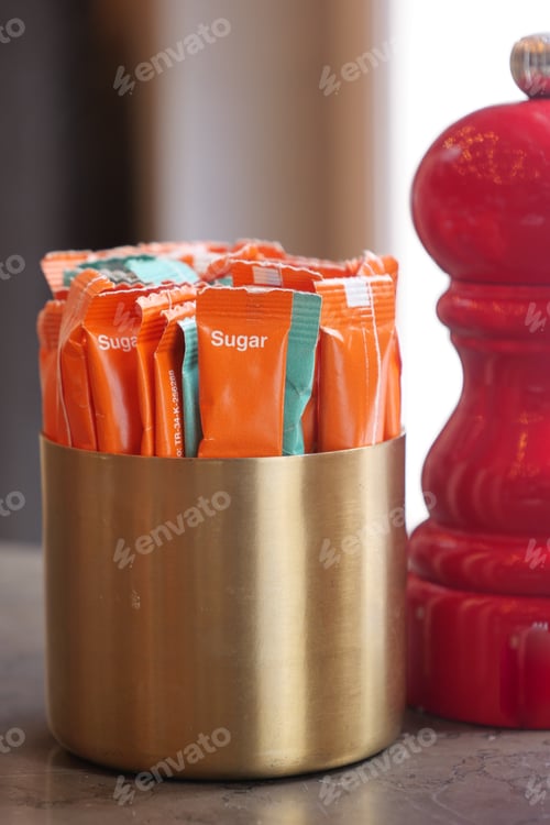 Preview: Sugar packets displayed in a brass holder on a table