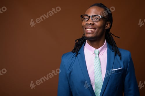 Preview: Young handsome African businessman wearing eyeglasses against br