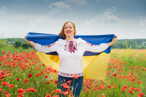 Preview: Girl carries fluttering blue and yellow flag of Ukraine in field.