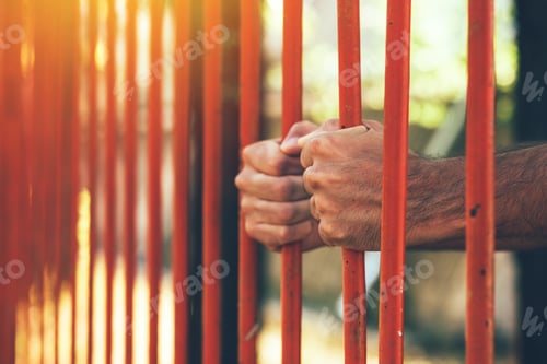 Preview: Male hands behind prison yard bars