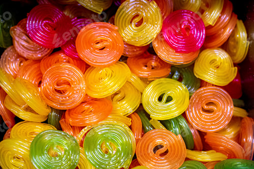 Preview: Multicolored jelly swirl candies background - yellow, red, orange transparent rolls.