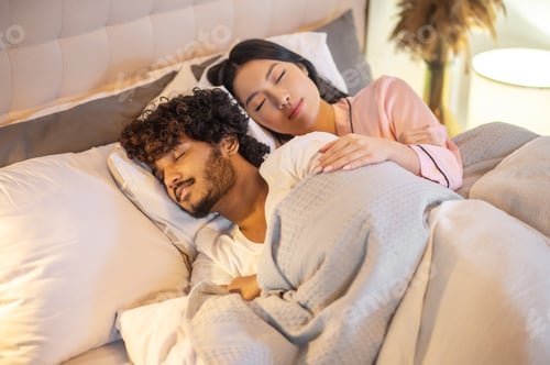 Preview: Woman hugging man lying in bed with closed eyes