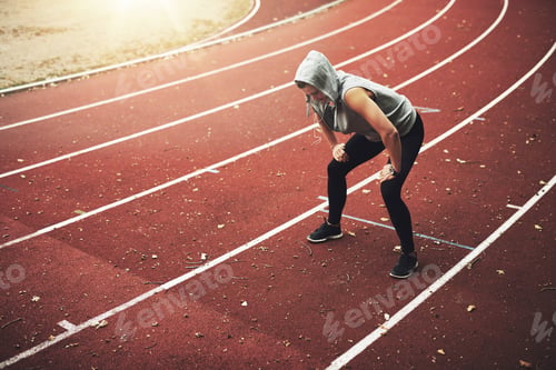 Preview: Young female runner standing on stadium and listening to music