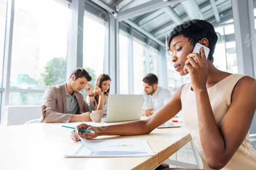 Preview: Businesswoman working and talking on cell phone at business meeting