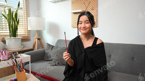 Preview: Cheerful teenage girls holding paintbrushes and smiling to camera.